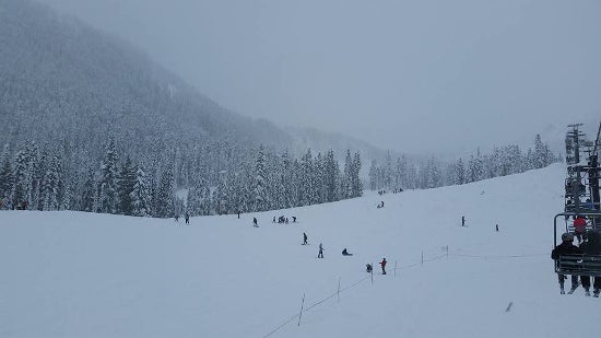 A snowy ski mountain with skiers descending the mountain
